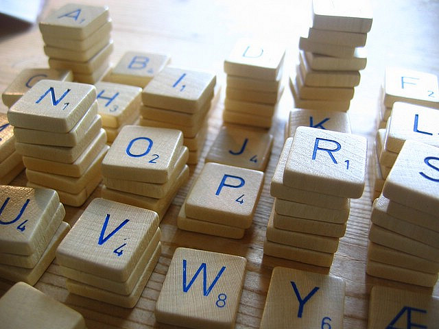 Stacks of white Scrabble tiles, with blue letters