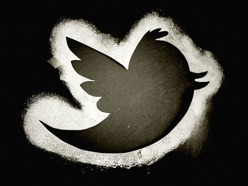 Graffiti of a black Twitter bird outlined in white on a black background.