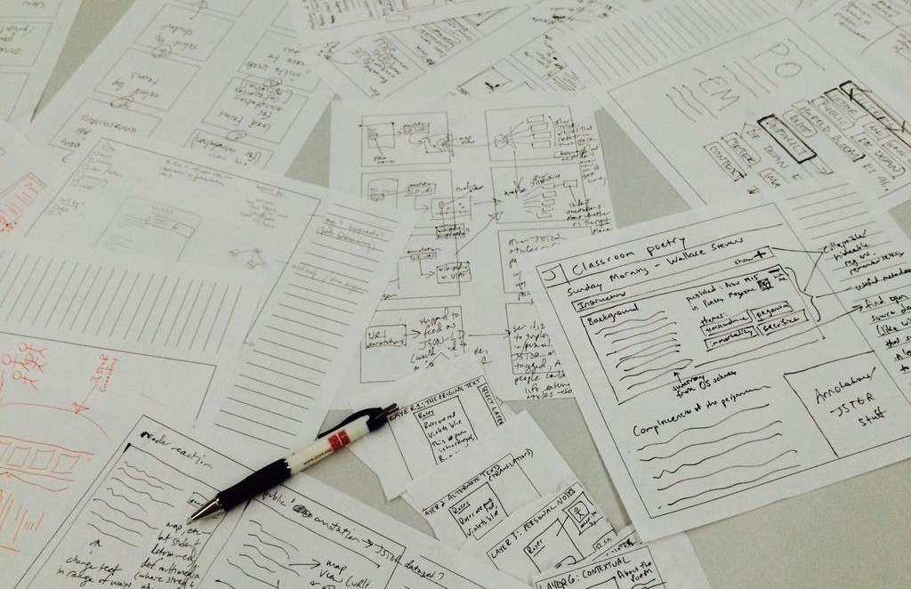 Sheets of paper with hand-drawn sketches of a web annotation interface, lying on a table.
