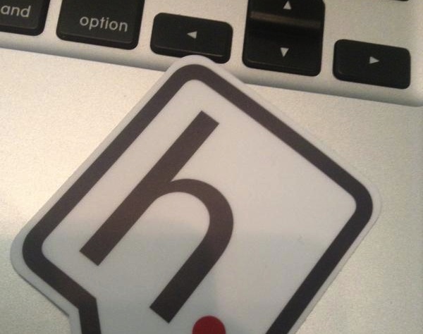 A sticker showing the hypothes.is logo--a black lower-case 'h' in a square speech bubble--on a Macbook keyboard