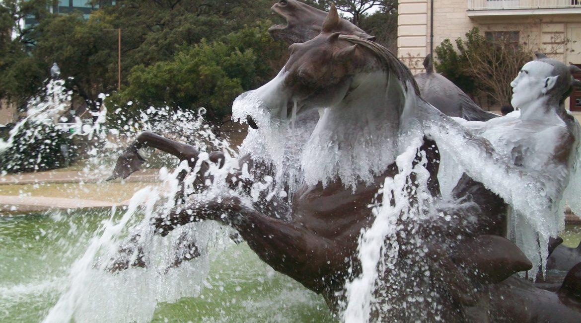 side view of the Littlefield fountain, statue. the fountain is frozen midstream.