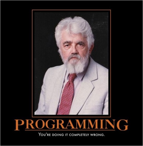 A grey-haired man in a grey suit and red tie looking out from a black background directly at the viewer. The caption reads "Programming: You're doing it completely wrong."