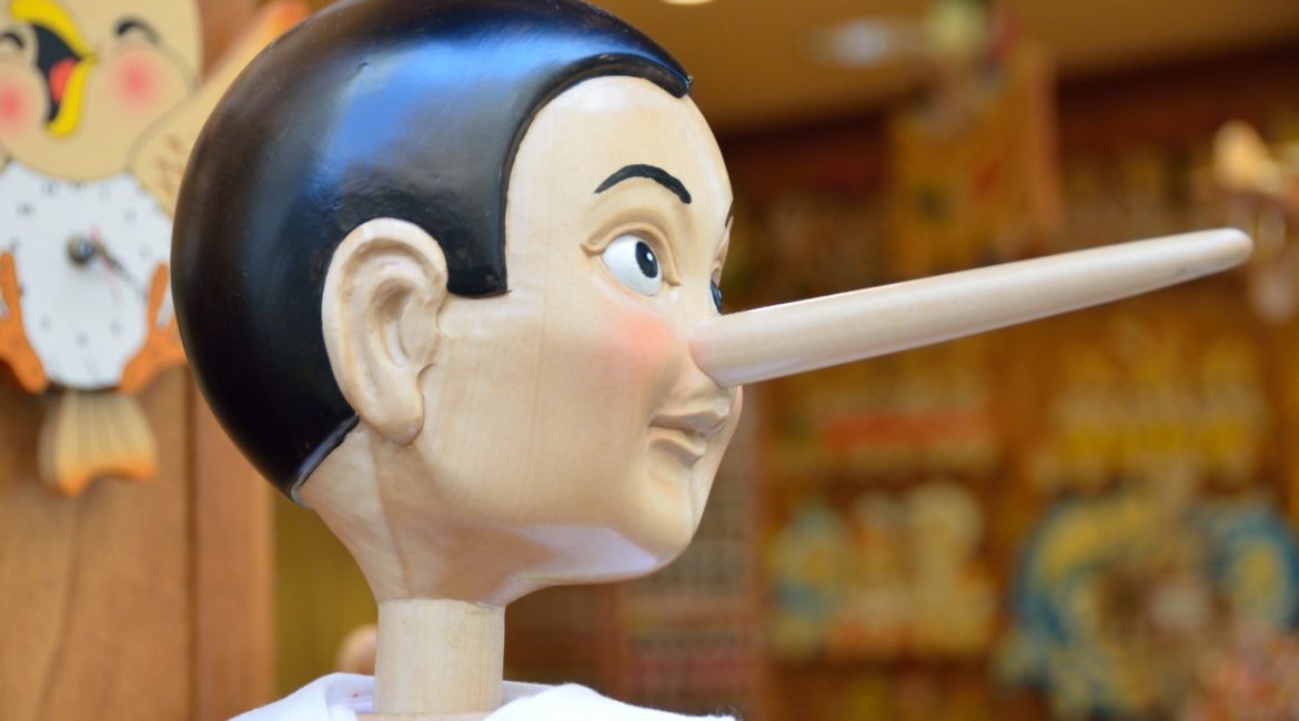 A wooden Pinocchio puppet, long nose pointing to the right.