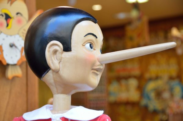 A wooden Pinocchio puppet, long nose pointing to the right.
