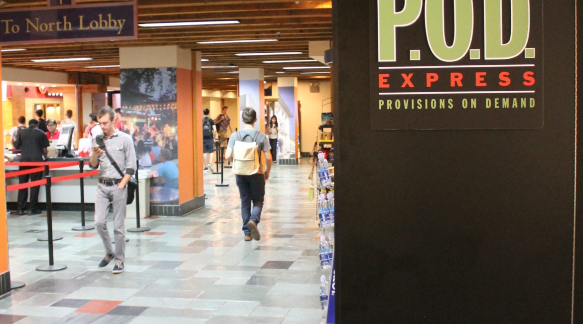 Photo of Provisions On Demand food kiosk in the Texas Union building. Black box at right with "P.O.D" label; students walking past on left