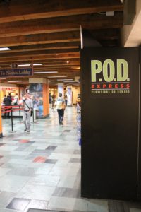 Photo of Provisions On Demand food kiosk in the Texas Union building. Black box at right with "P.O.D" label; students walking past on left