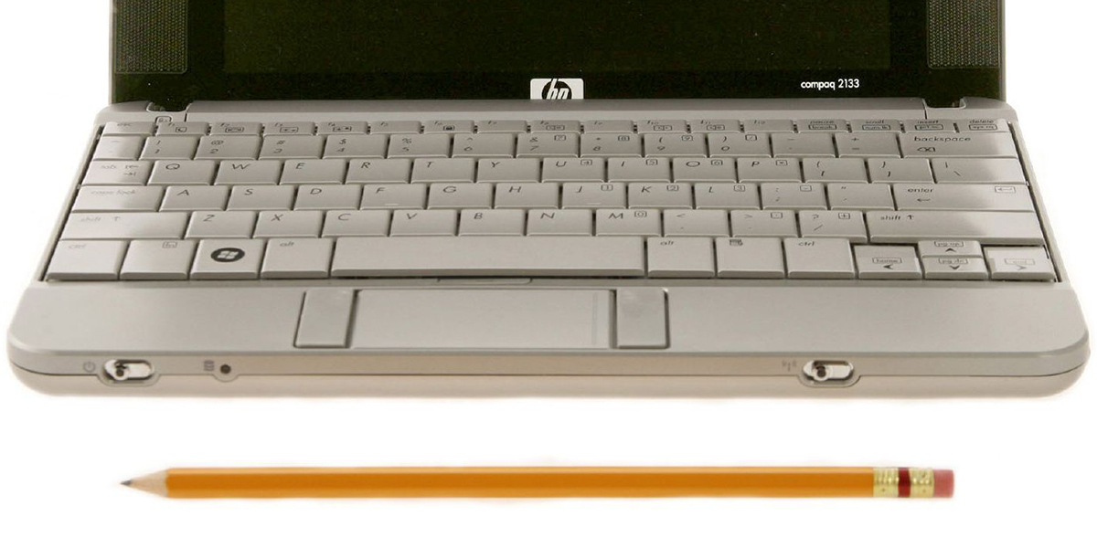 Image of a sharpened graphite pencil in front of a laptop keyboard; white background