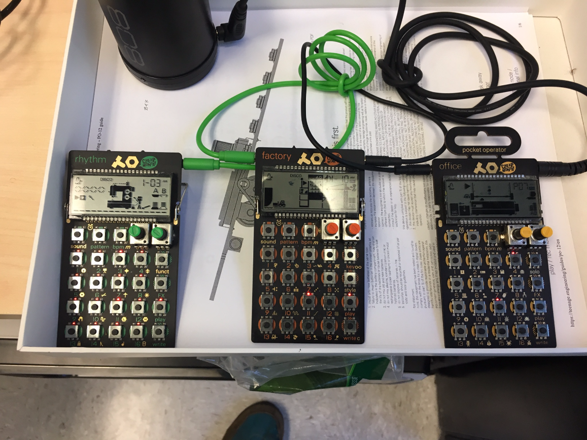 Three calculator instruments that are plugged into one another, in a small white box. These instruments communicate with eachother and stay synced, allowing for the experience of a micro-production studio