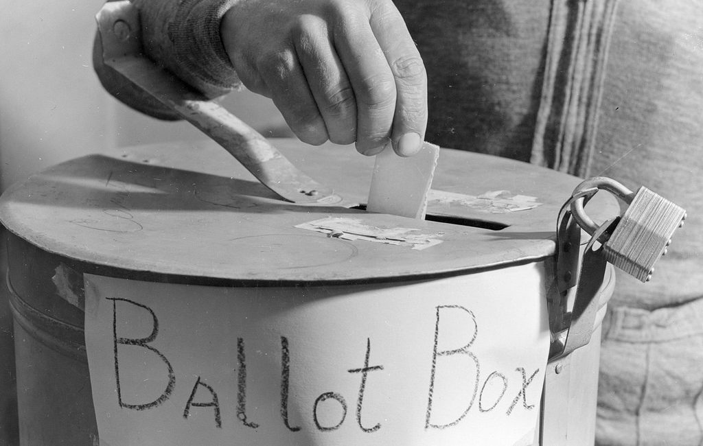 Hand dropping ballot in a locked ballot box